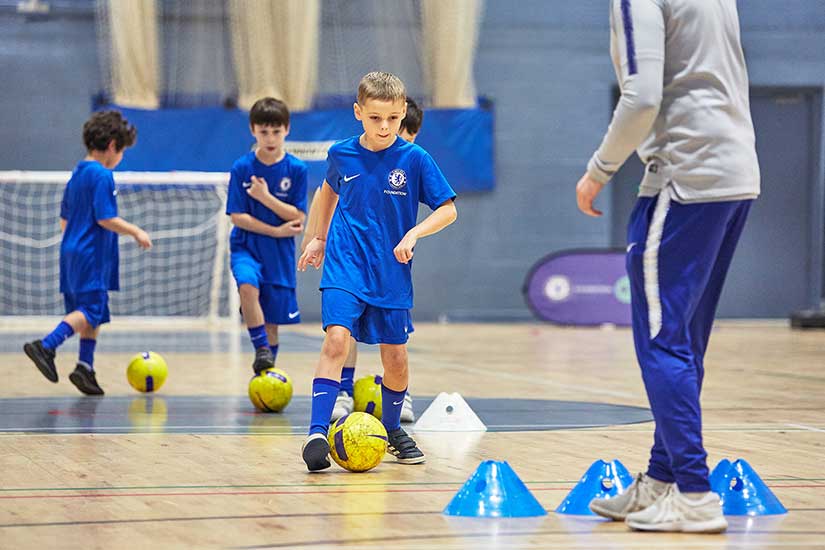 Children with coach at school holiday football camp